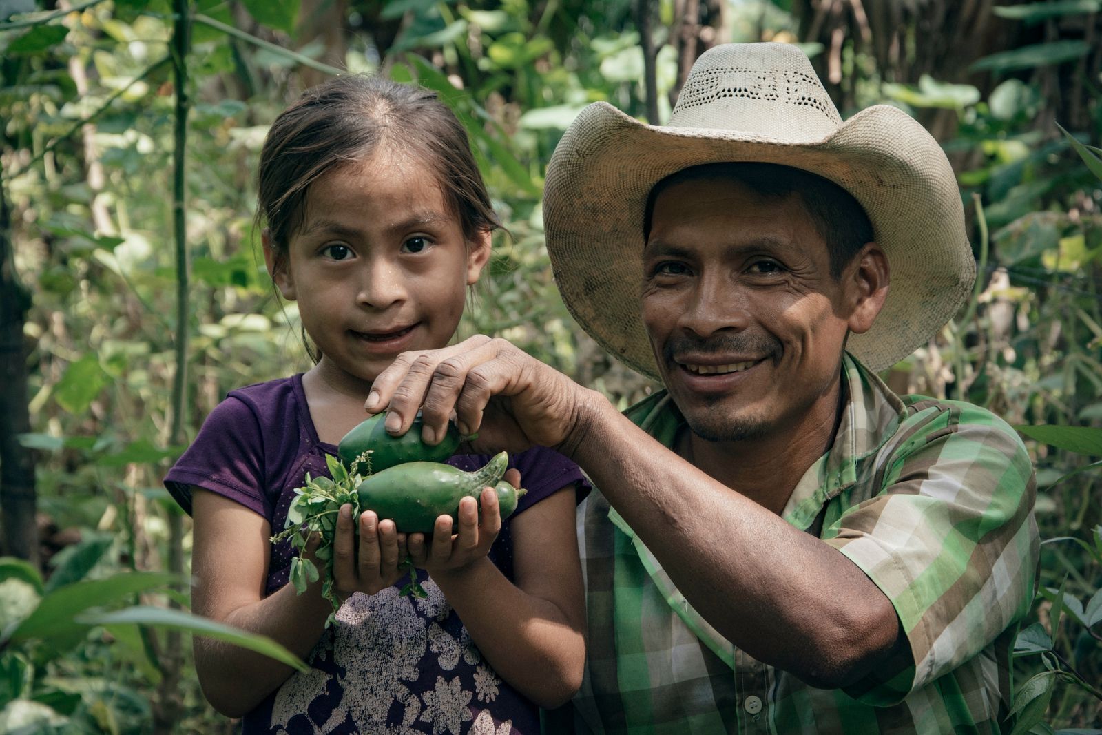 A father and daughter smiling in a vegetable garden